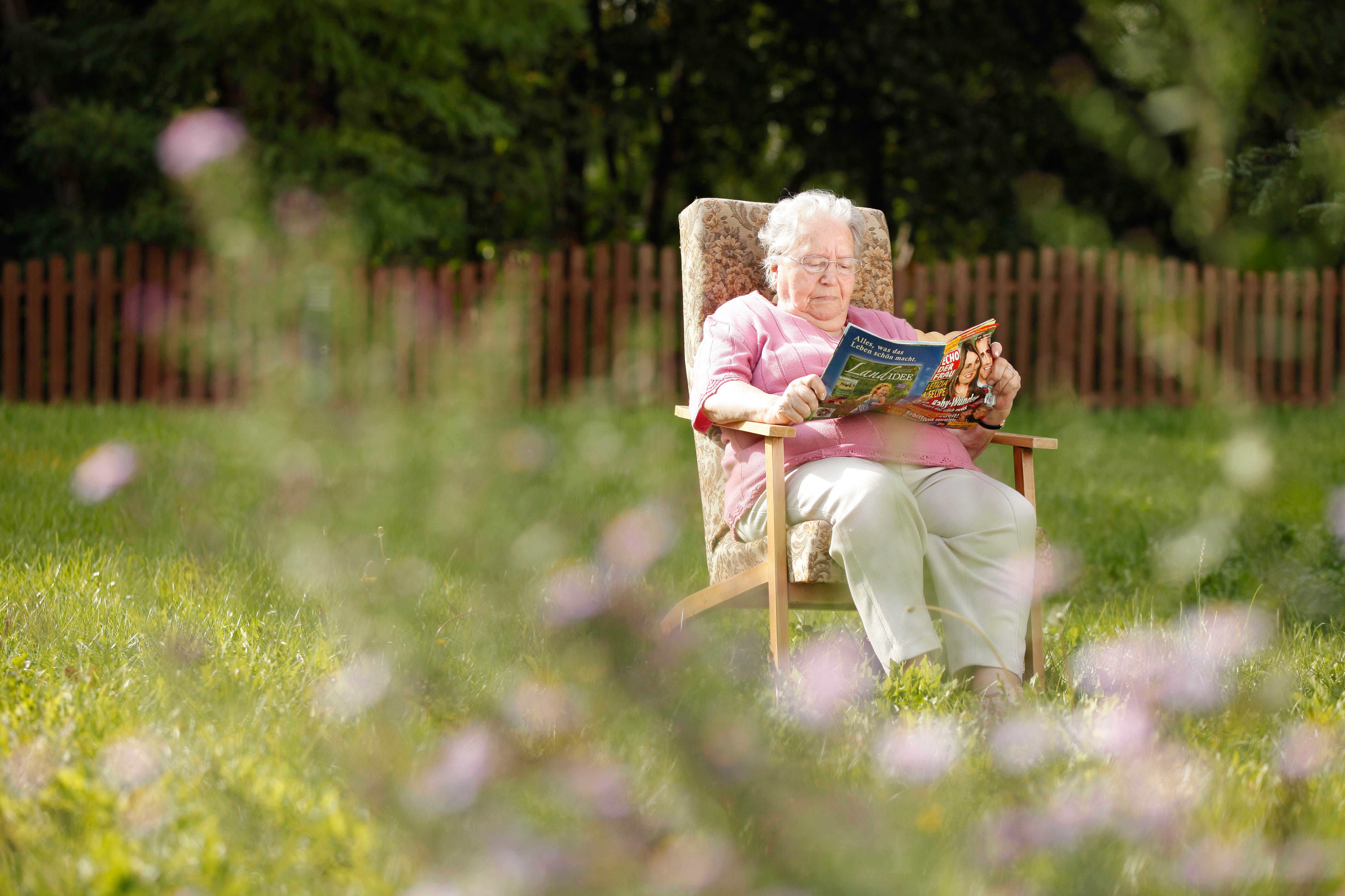 Eine Seniorin sitzt im Garten